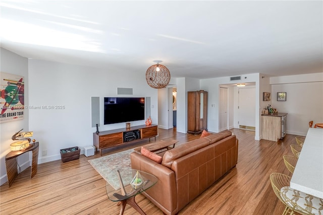 living area featuring baseboards, visible vents, and light wood-style floors