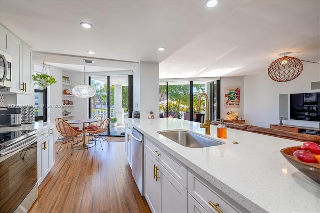 kitchen with white cabinetry, a sink, appliances with stainless steel finishes, and wood finished floors