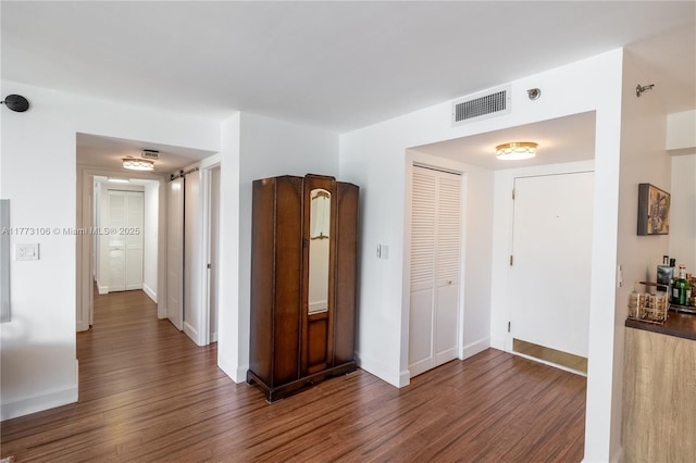 hall with dark wood-type flooring, baseboards, and visible vents