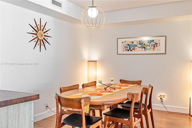 dining area featuring baseboards, light wood-style floors, and visible vents