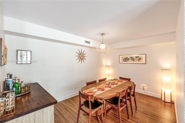 dining area with baseboards, visible vents, and wood finished floors