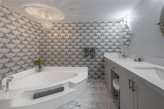 full bath featuring marble finish floor, double vanity, a sink, a garden tub, and a notable chandelier