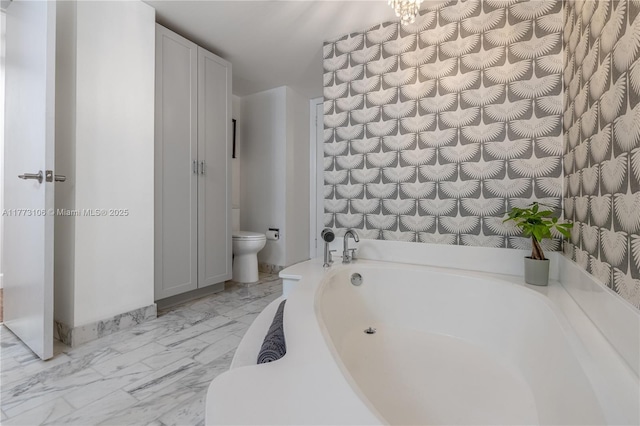 full bathroom featuring marble finish floor, toilet, and a bath
