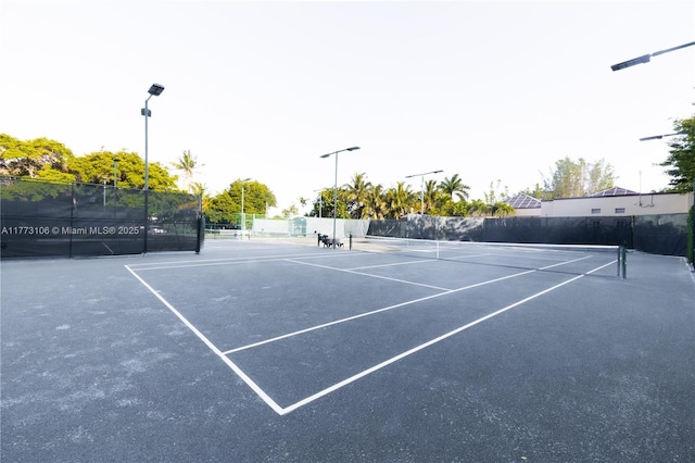 view of tennis court with community basketball court and fence
