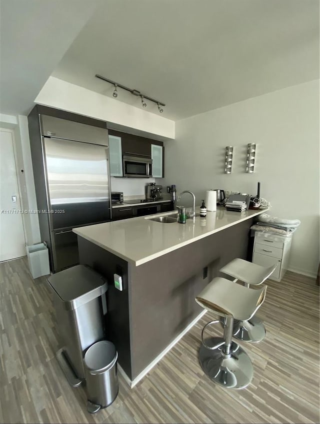 55 SE 6th St Unit 1506, Miami, FL 33131 - kitchen with a sink, a breakfast bar area, appliances with stainless steel finishes, and wood finished floors