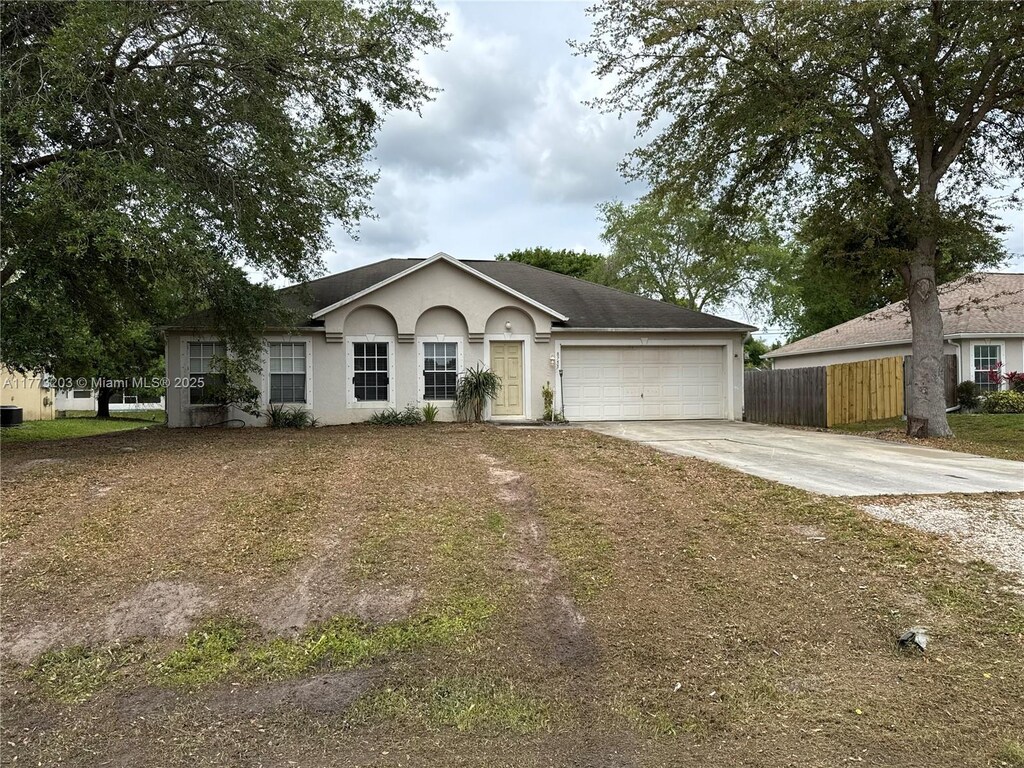 8755 103rd Ct, Vero Beach, FL 32967 - ranch-style home with driveway, an attached garage, fence, and stucco siding