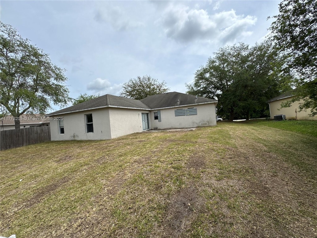 8755 103rd Ct, Vero Beach, FL 32967 - back of house with central AC unit, stucco siding, fence, and a yard