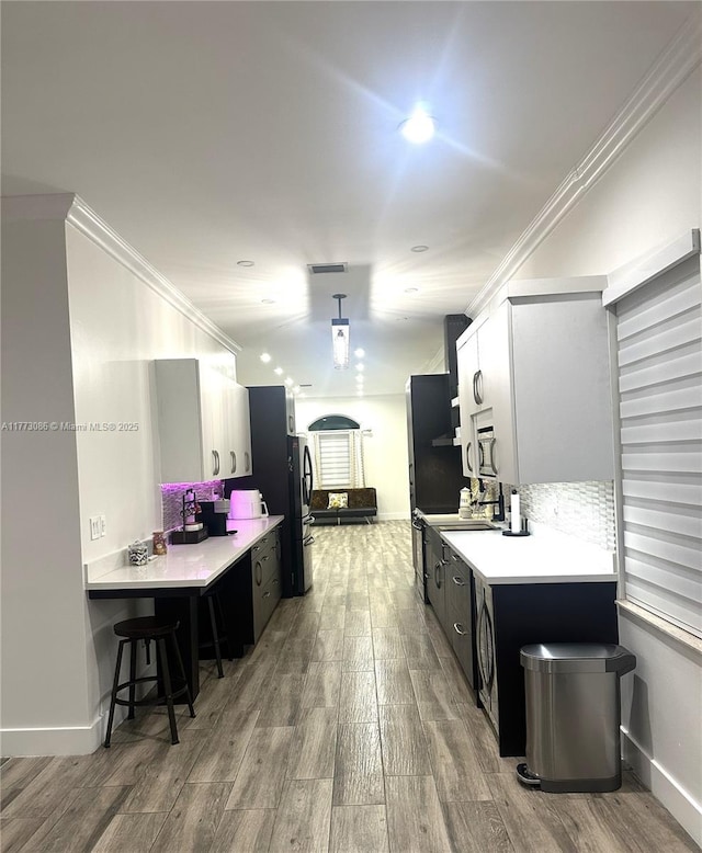 11845 SW 3rd St, Miami, FL 33184 - kitchen featuring light countertops, crown molding, light wood-type flooring, dark cabinetry, and freestanding refrigerator