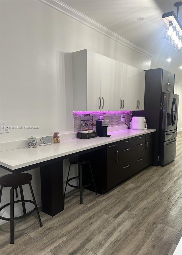 11845 SW 3rd St, Miami, FL 33184 - kitchen featuring light countertops, a kitchen bar, stainless steel refrigerator with ice dispenser, crown molding, and wood finished floors