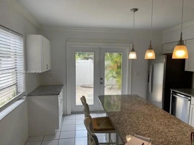 1494 SW 32nd Ct, Fort Lauderdale, FL 33315 - kitchen with stainless steel appliances, crown molding, light tile patterned floors, white cabinets, and french doors