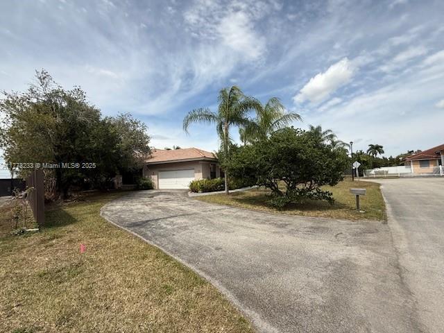 view of front of house featuring driveway, a front yard, and a garage