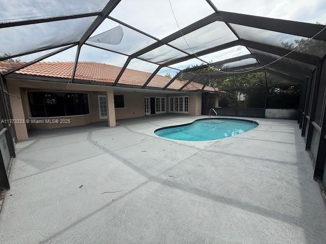 outdoor pool featuring glass enclosure and a patio