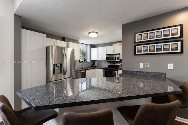 1401 NE 9th St Unit 26, Fort Lauderdale, FL 33304 - kitchen with white cabinets, a peninsula, stainless steel appliances, a sink, and a breakfast bar area