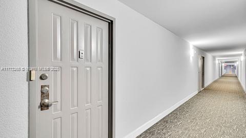 corridor featuring carpet flooring and baseboards