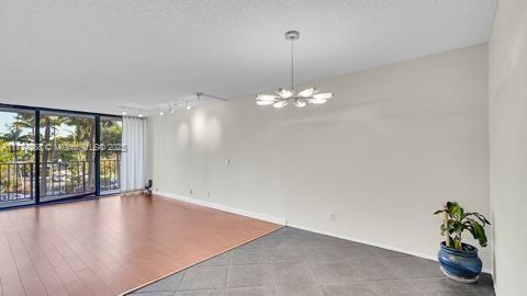 unfurnished room with a wall of windows, rail lighting, and a chandelier