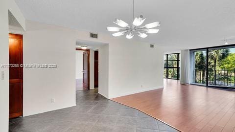 unfurnished room featuring an inviting chandelier, floor to ceiling windows, and visible vents