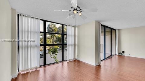 empty room featuring baseboards, a ceiling fan, floor to ceiling windows, and wood finished floors