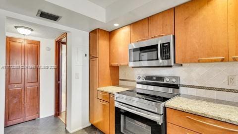 kitchen featuring appliances with stainless steel finishes, light stone counters, baseboards, tasteful backsplash, and visible vents