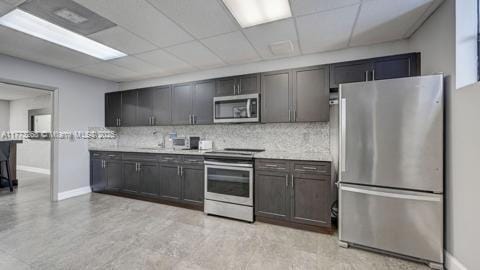 kitchen featuring light countertops, a paneled ceiling, tasteful backsplash, and stainless steel appliances
