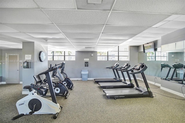 workout area featuring a healthy amount of sunlight, baseboards, a drop ceiling, and carpet flooring