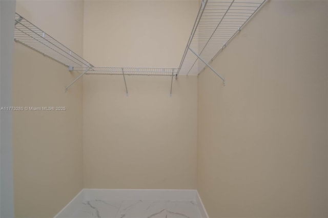 walk in closet featuring marble finish floors