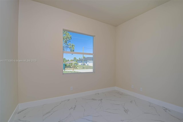 spare room with baseboards and marble finish floors