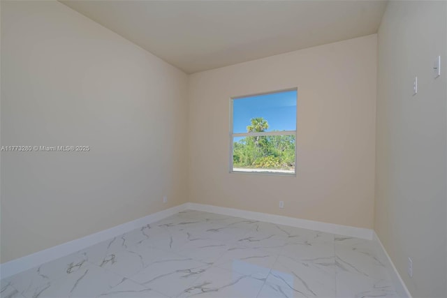unfurnished room featuring light marble finish floors and baseboards