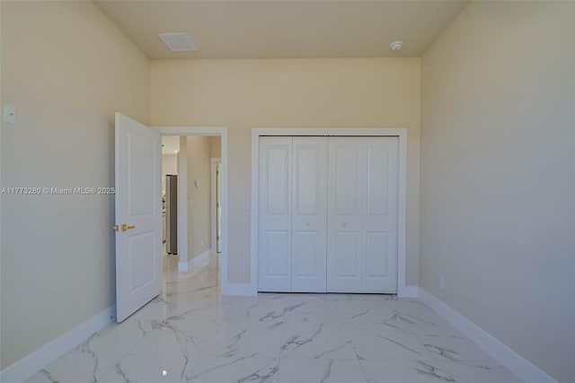 unfurnished bedroom with baseboards, light marble finish flooring, and a closet