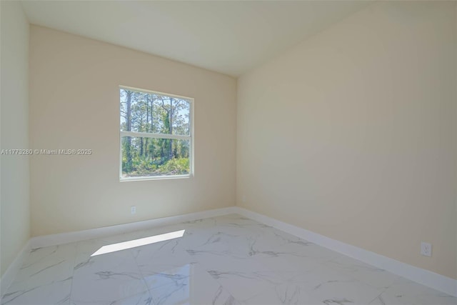 unfurnished room featuring baseboards and marble look tiles