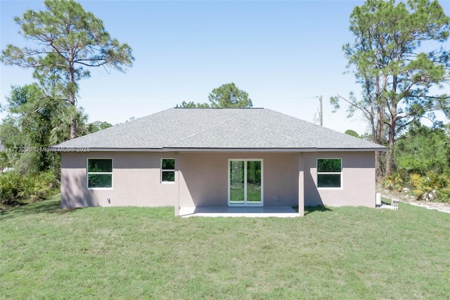 rear view of house featuring stucco siding, a shingled roof, a yard, and a patio area