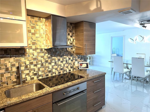 427 Golden Isles Dr Unit 5G, Hallandale Beach, FL 33009 - kitchen featuring black electric stovetop, wall chimney range hood, backsplash, wall oven, and marble finish floor