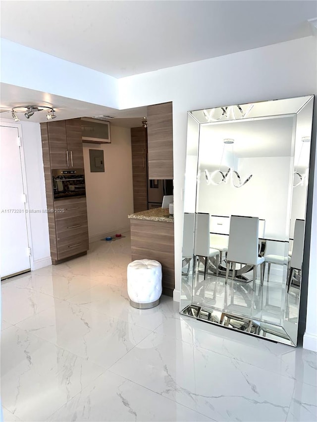 427 Golden Isles Dr Unit 5G, Hallandale Beach, FL 33009 - kitchen with electric panel, marble finish floor, and brown cabinetry