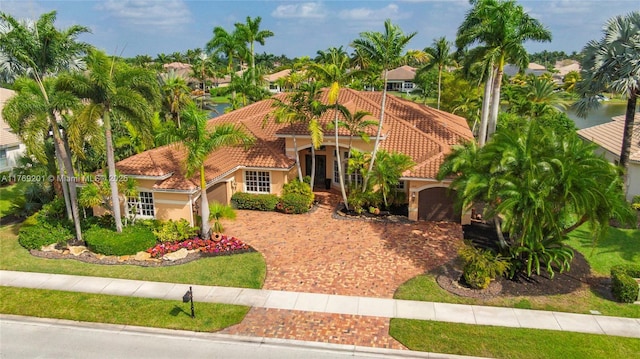 mediterranean / spanish home with a tile roof, a garage, driveway, and stucco siding