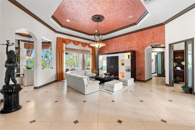 living area with a tray ceiling, crown molding, baseboards, light tile patterned flooring, and arched walkways
