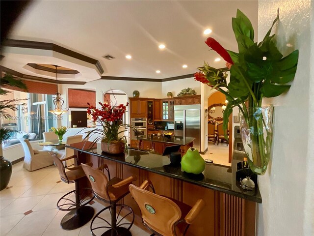 kitchen featuring visible vents, stainless steel appliances, dark countertops, a sink, and brown cabinetry