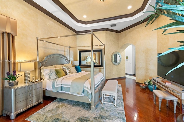 bedroom featuring visible vents, crown molding, arched walkways, and wood-type flooring