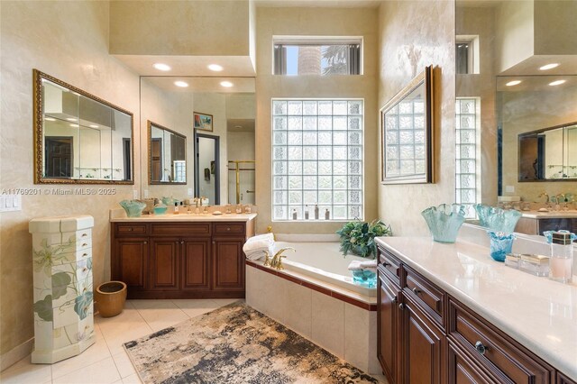 full bath featuring a sink, a garden tub, tile patterned floors, and two vanities