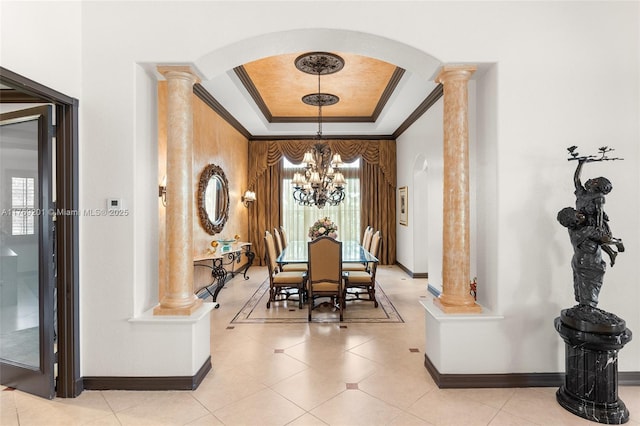dining area featuring a tray ceiling, ornate columns, arched walkways, ornamental molding, and an inviting chandelier