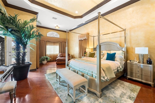 bedroom with wood finished floors, crown molding, a tray ceiling, and visible vents