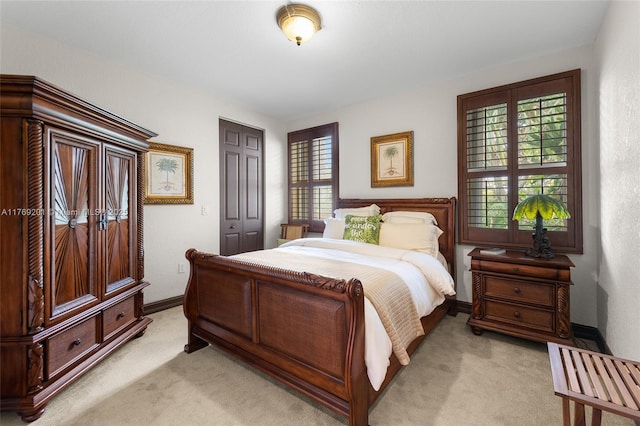 bedroom with baseboards, a closet, and light colored carpet