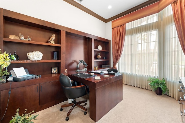 home office with built in shelves, crown molding, and light colored carpet