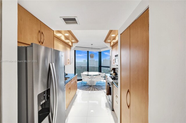 20281 E Country Club Dr Unit 1002, Aventura, FL 33180 - kitchen featuring stainless steel fridge, range with gas stovetop, light tile patterned floors, white microwave, and a wall of windows