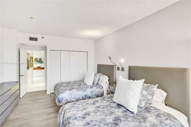 20281 E Country Club Dr Unit 1002, Aventura, FL 33180 - bedroom featuring light wood-style flooring, a textured ceiling, and a closet