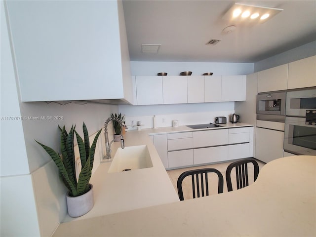 16901 Collins Ave Unit 1404, Sunny Isles Beach, FL 33160 - kitchen featuring stainless steel appliances, white cabinets, and light countertops