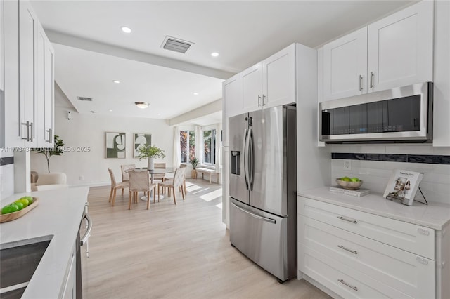 74 NE 103rd St, Miami Shores, FL 33138 - kitchen with stainless steel appliances, white cabinetry, backsplash, light wood-style flooring, and recessed lighting