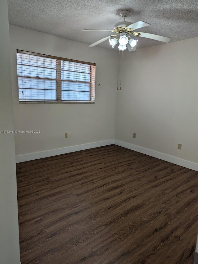 empty room featuring dark wood finished floors, baseboards, ceiling fan, and a textured ceiling