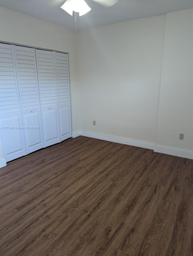 unfurnished bedroom with a closet, dark wood-style floors, and baseboards