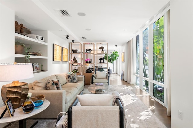 living area featuring visible vents, wood finished floors, and floor to ceiling windows