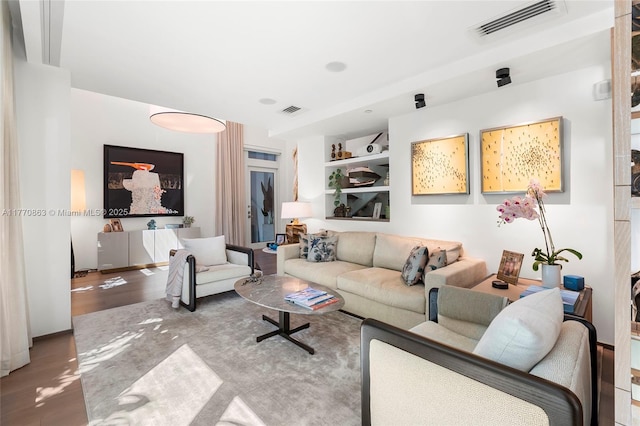living area with visible vents, wood finished floors, and built in shelves