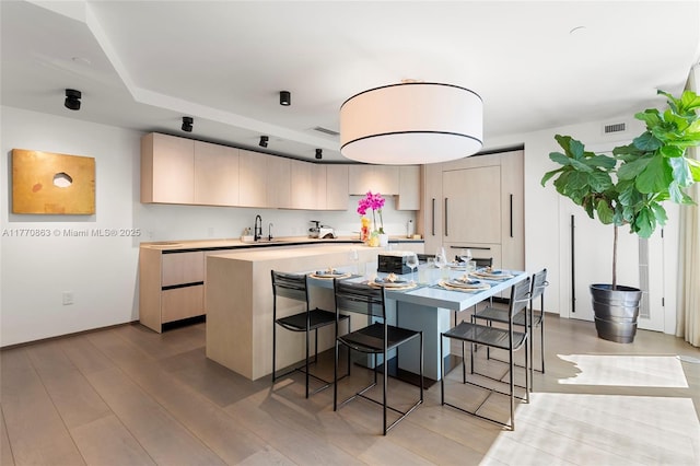 kitchen featuring a sink, a center island, a breakfast bar area, visible vents, and light countertops